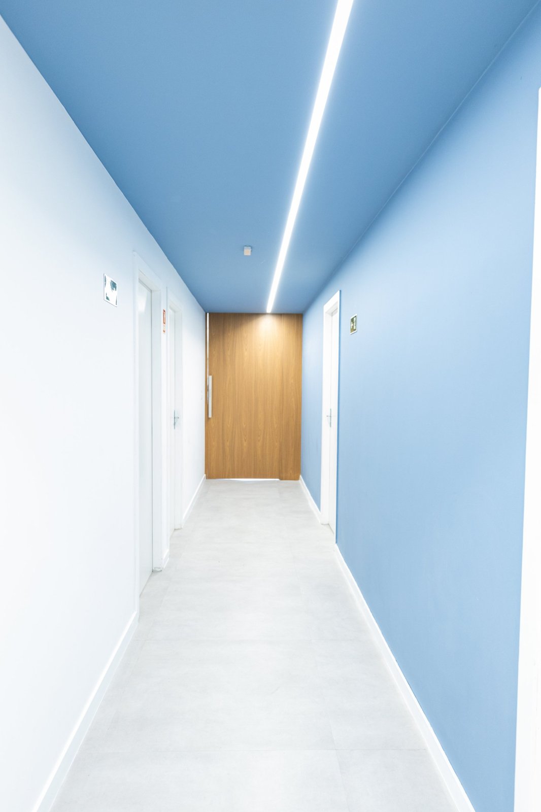 Corredor com teto azul e porta de madeira ao fundo