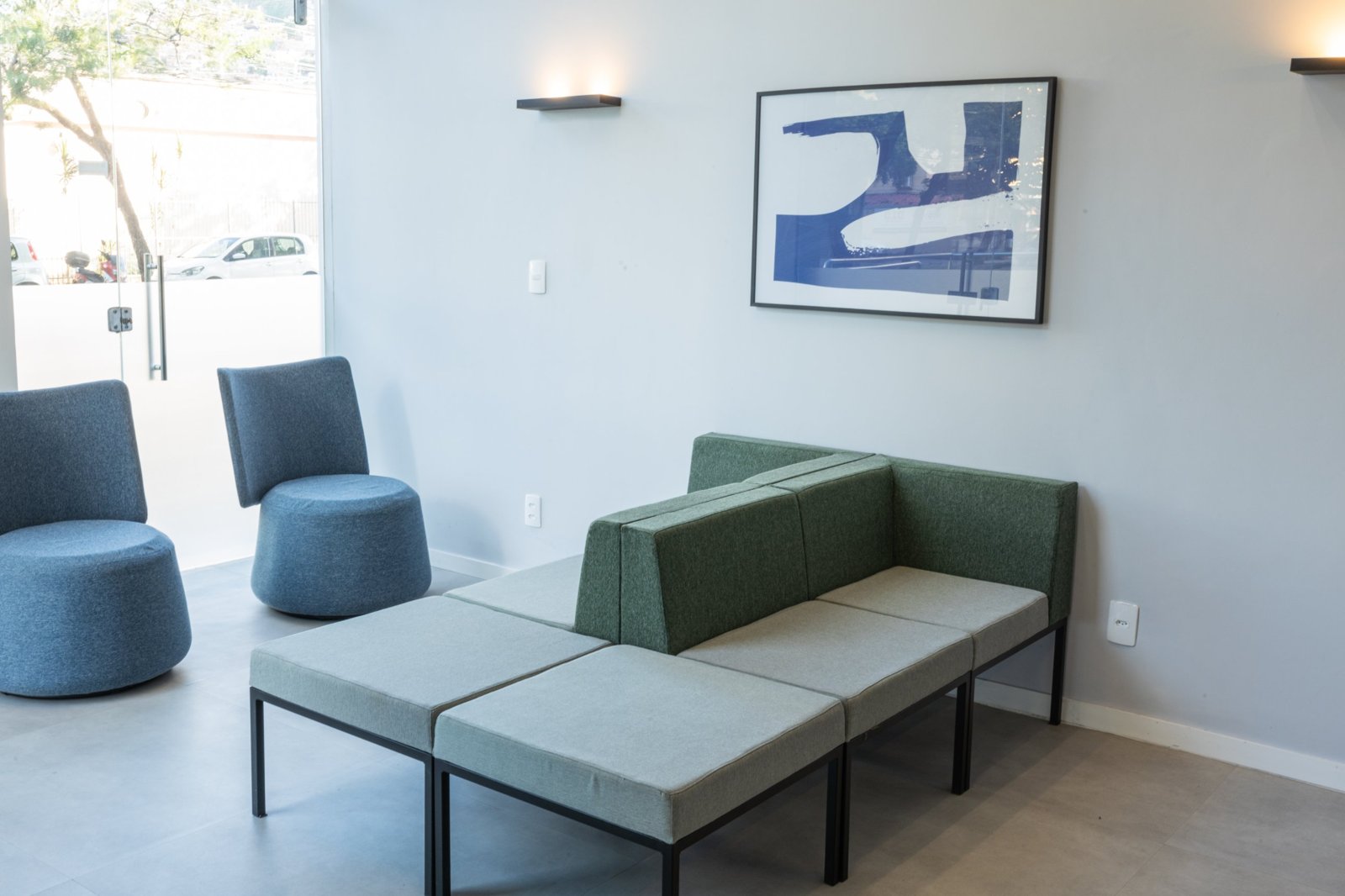 Recepção com poltronas azuis e sofá verde