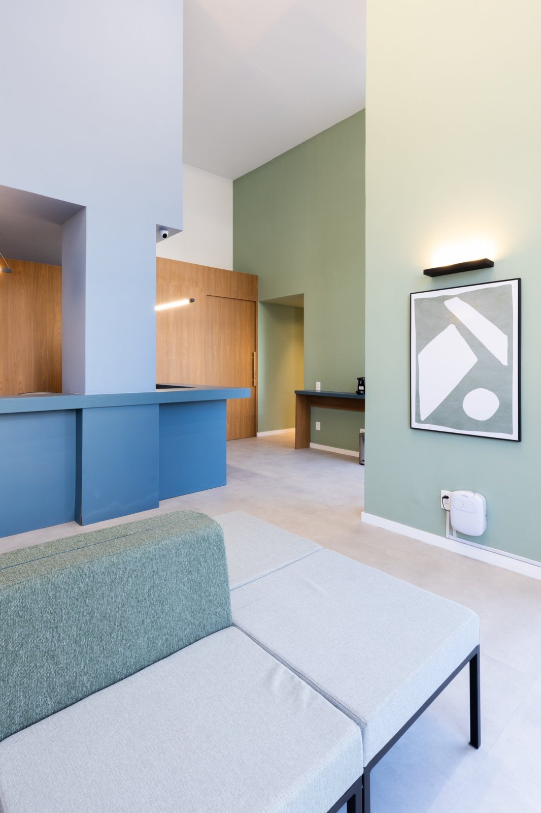 Recepção da DocSpace com balcão azul, parede verde e sofá em primeiro plano