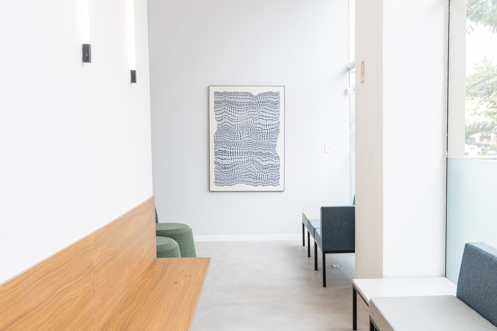 Sala de espera com banco de madeira e quadro azul ao fundo